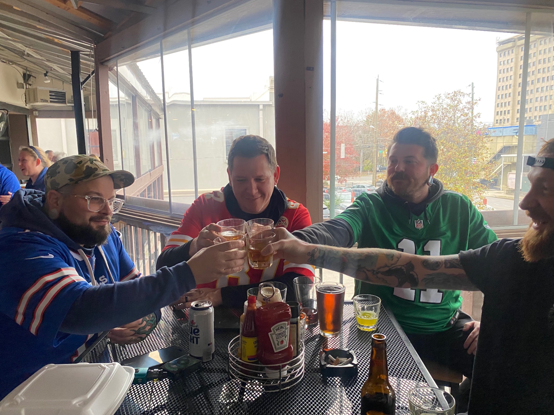 Friends in football jerseys raising a toast on the Crow's Nest covered patio